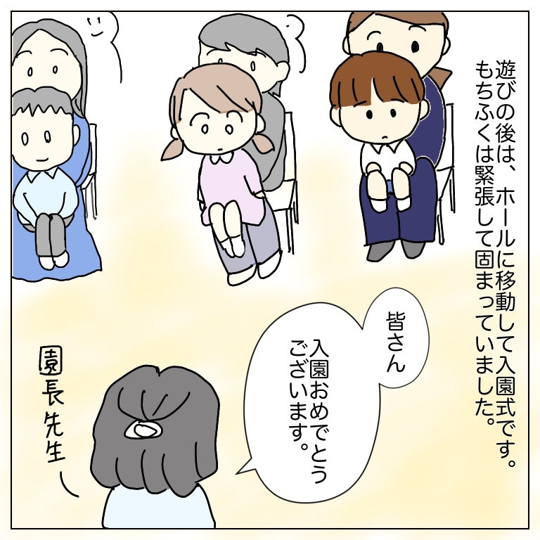 ホールで入園式のイラスト。母の膝に座る息子